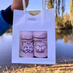 Coffret cadeau de naissance. Des chaussettes bébé dépareillées avec un chat et une souris.